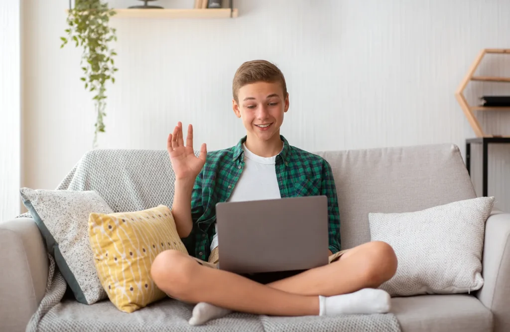Teenage boy video calling on a laptop at home